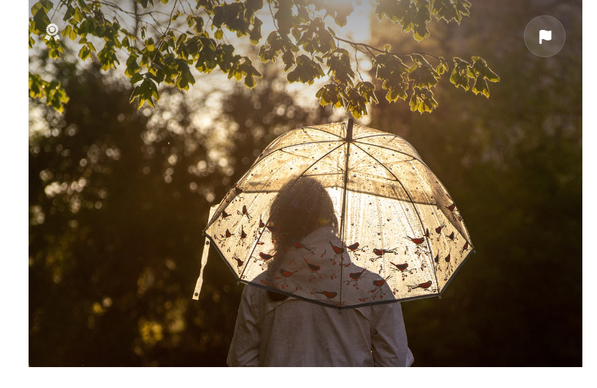 Wanderin mit transparentem Regenschirm im Gegenlicht
