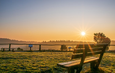 Sonnenaufgang über Heidefläche mit Nebel, Wacholder und blauem Himmel.